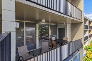 A balcony with a table and chairs, a window, and a railing. - Cozy Island Escape - Near Waikiki & Diamond Head (Honolulu)