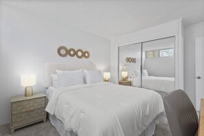 Ein Hotelzimmer mit einem großen Bett, Nachttischen mit Lampen, einem Spiegel und einem Kleiderschrank.