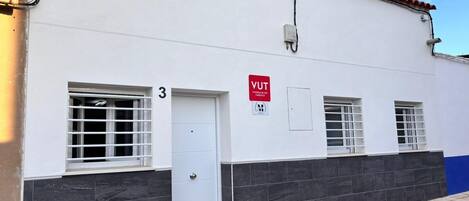 Un edificio con fachada blanca, número 3, y un letrero rojo que indica un alojamiento turístico.