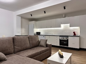 A modern kitchen with white cabinets, a built-in oven, and a microwave.