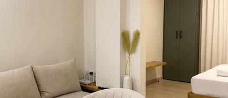Quarto de hotel moderno com área de refeições, sofá, cama e armário.