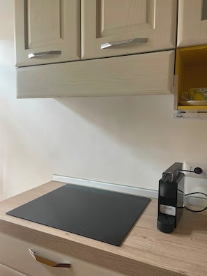 Eine Küche mit Arbeitsplatte, einer schwarzen Matte, einer Kaffeemaschine und einer Steckdose.