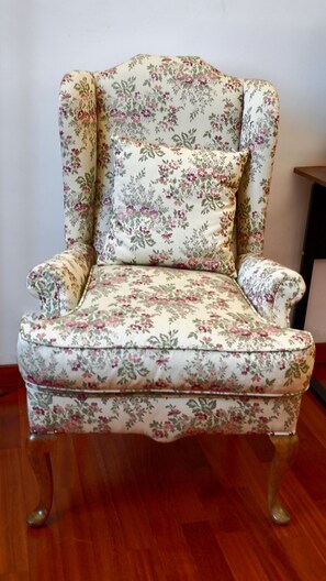 A floral-patterned armchair with a cushioned seat and backrest, positioned on a wooden floor. - Near Me:Mansio Portus,Civitavecchia, Railroad,Port, Cruise Ships,Rome,Etruscans (Civitavecchia)
