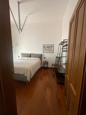 A bedroom with a bed, a nightstand, a chair, a ladder, and a door.