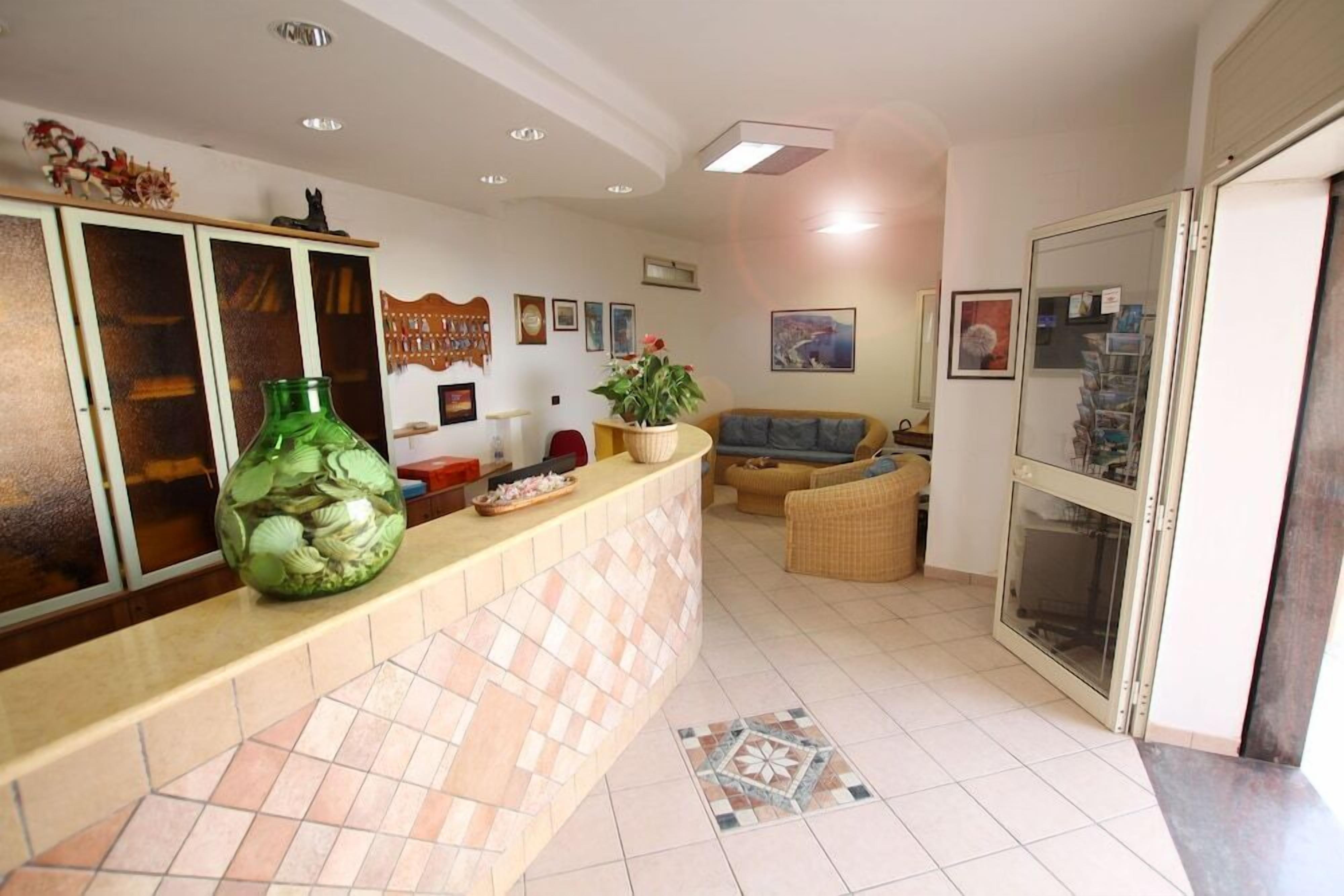 A reception area with a tiled counter, a green vase, and a sofa.