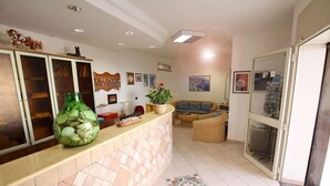 Una zona de recepción con mostrador de baldosas, un jarrón verde y un sofá.