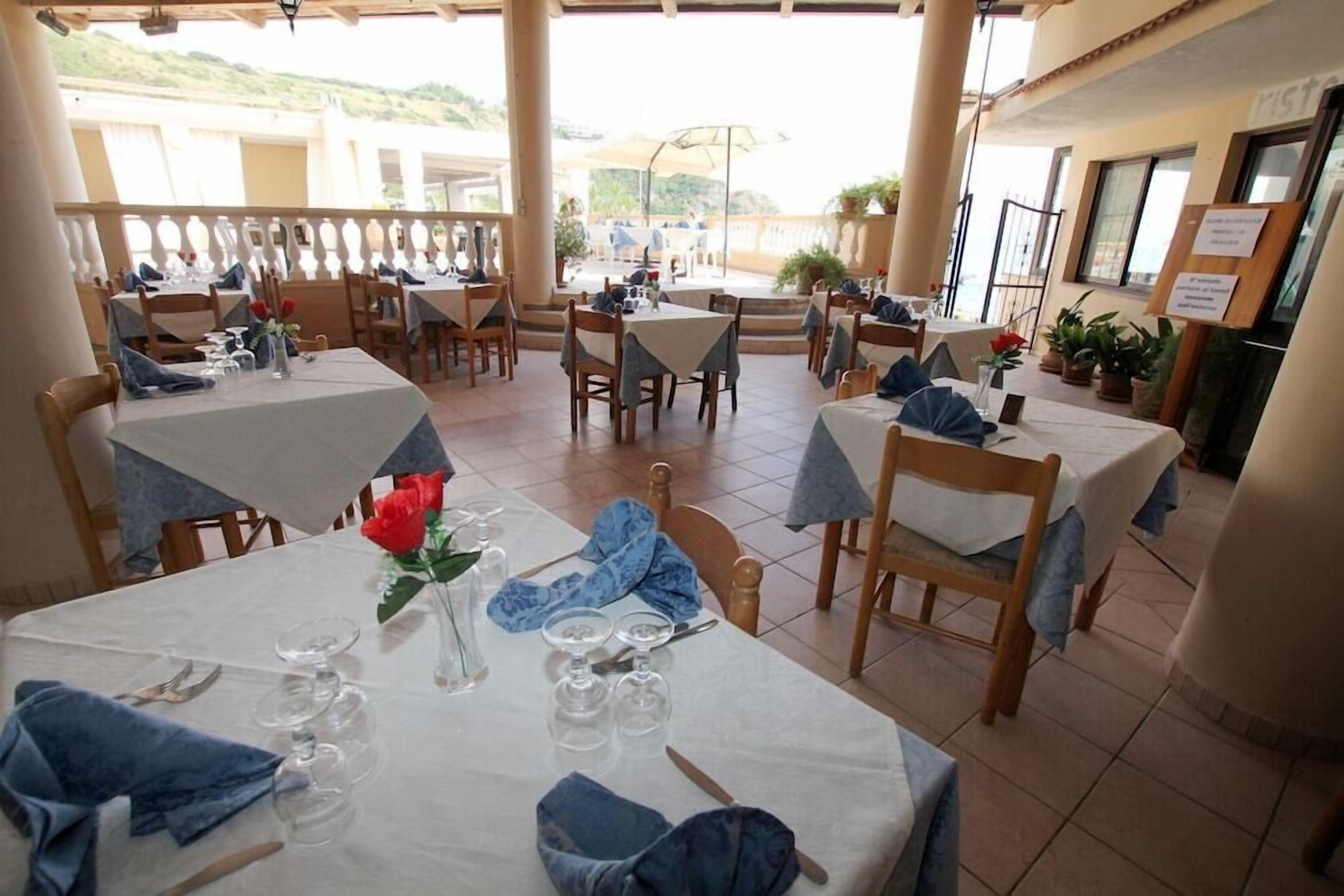A restaurant with multiple tables, each set with cutlery, glasses, and napkins.