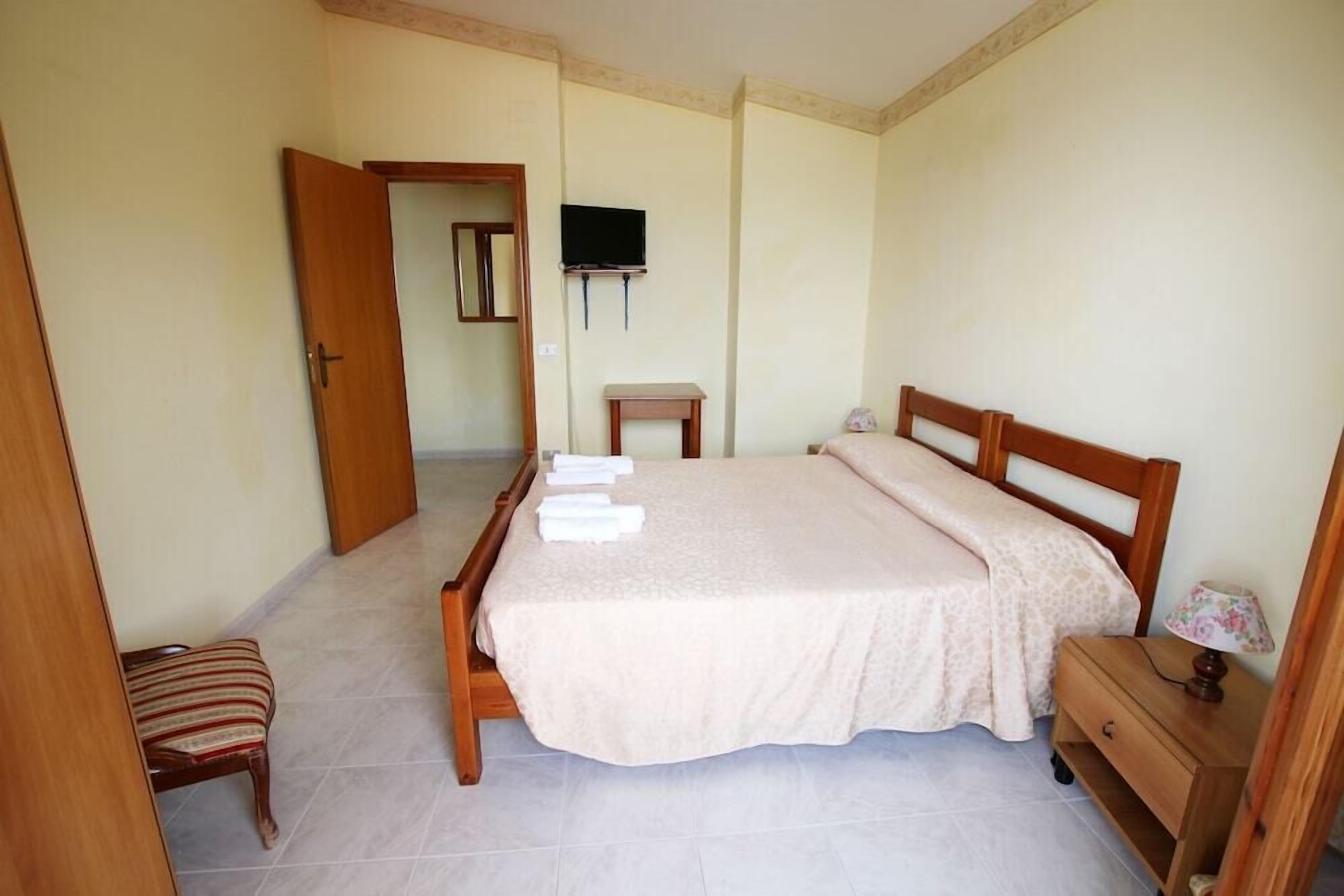 Una camera da letto con un letto, una televisione, un tavolino, una sedia e un comodino.