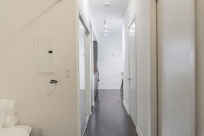 A narrow hallway with doors on both sides, a light switch, and a power outlet on the wall. - CN Tower View 2-Bed+den, with parking 8 Guests (Toronto)