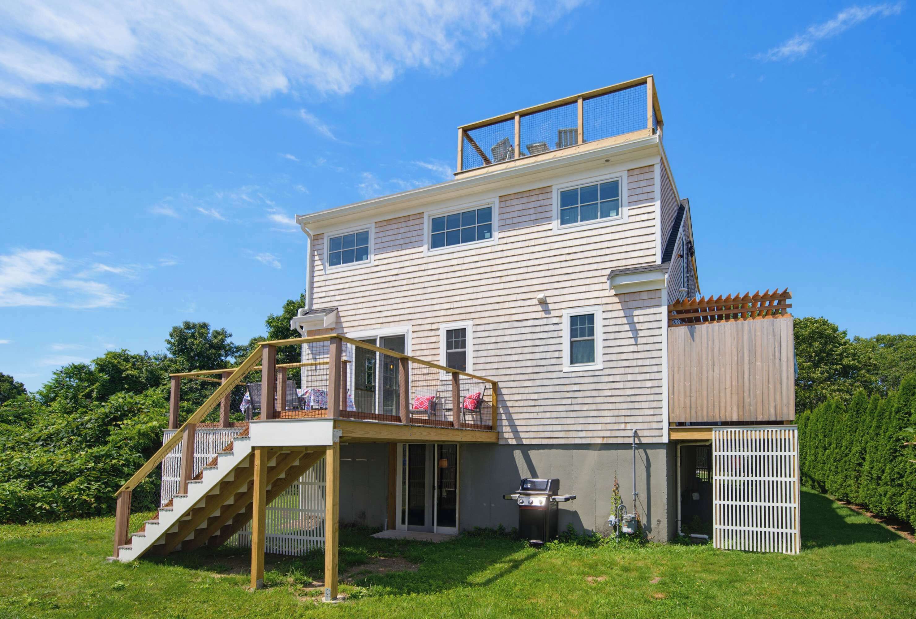 Una casa de dos pisos con balcón, escaleras y un patio cercado.