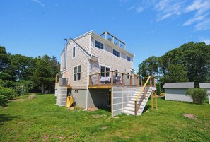 A two-story house with a covered deck and a staircase leading to the upper level. - Walk To The Beach, Rooftop Deck With Water Views (Bourne)
