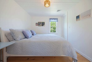 A bedroom with a bed, a window, and a ceiling light fixture. - Walk To The Beach, Rooftop Deck With Water Views (Bourne)