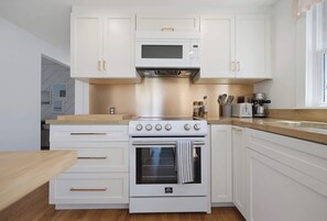 A modern kitchen with white cabinetry, a built-in oven, a microwave, and a stovetop with multiple burners. - Walk To The Beach, Rooftop Deck With Water Views (Bourne)