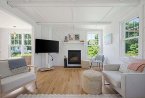 Un salon moderne avec une cheminée, un téléviseur à écran plat et de grandes fenêtres.