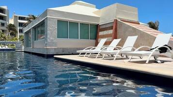 A swimming pool with lounge chairs and a building with large windows.
