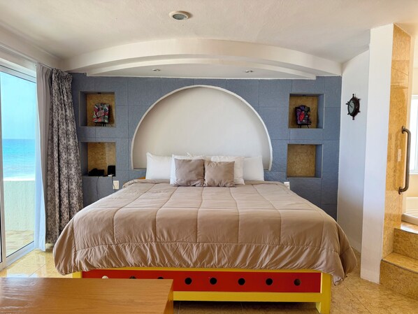 A bedroom with a large bed, a view of the sea, and a curved ceiling design.