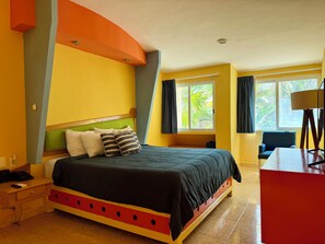 A hotel room with a bed, a desk, a lamp, and a window with curtains.