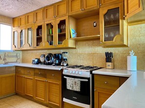 A kitchen with wooden cabinets, a stove, a coffee maker, and a knife block.