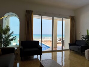 A spacious living area with a view of the beach and pool through large sliding glass doors.