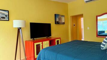 Een hotelkamer met een bed, een flatscreen televisie, een lamp en een schilderij aan de muur.