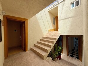 A staircase with a textured wall, a wooden door, and potted plants.