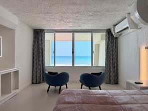 A bedroom with a large bed, two chairs, a TV, and a view of the sea. - Eight Bedroom Beachfront Villa - Private Heated Pool & Beach Access (Cancun)