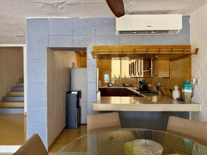 Une cuisine moderne dotée d’un îlot central, de meubles encastrés et d’un coin repas avec une table en verre.