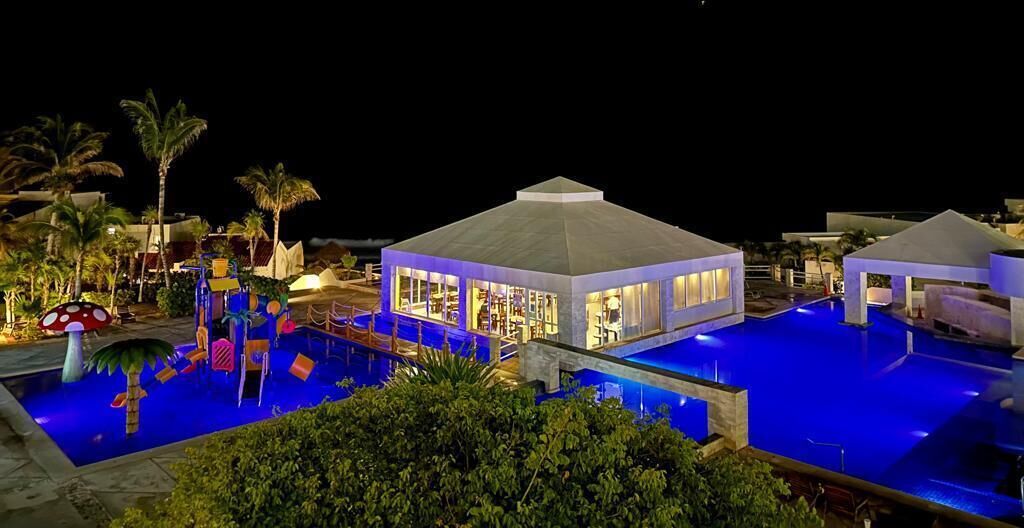 Een resort met een zwembad, een overdekt gedeelte en palmbomen.