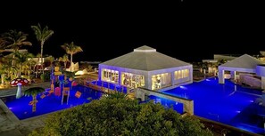Ein Resort mit Schwimmbad, überdachtem Bereich und Palmen.