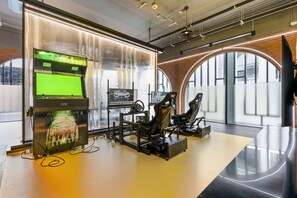 Ein moderner Gaming-Einrichtung mit Rennsimulator, zwei Monitoren und einem großen Fenster mit Stadtblick.