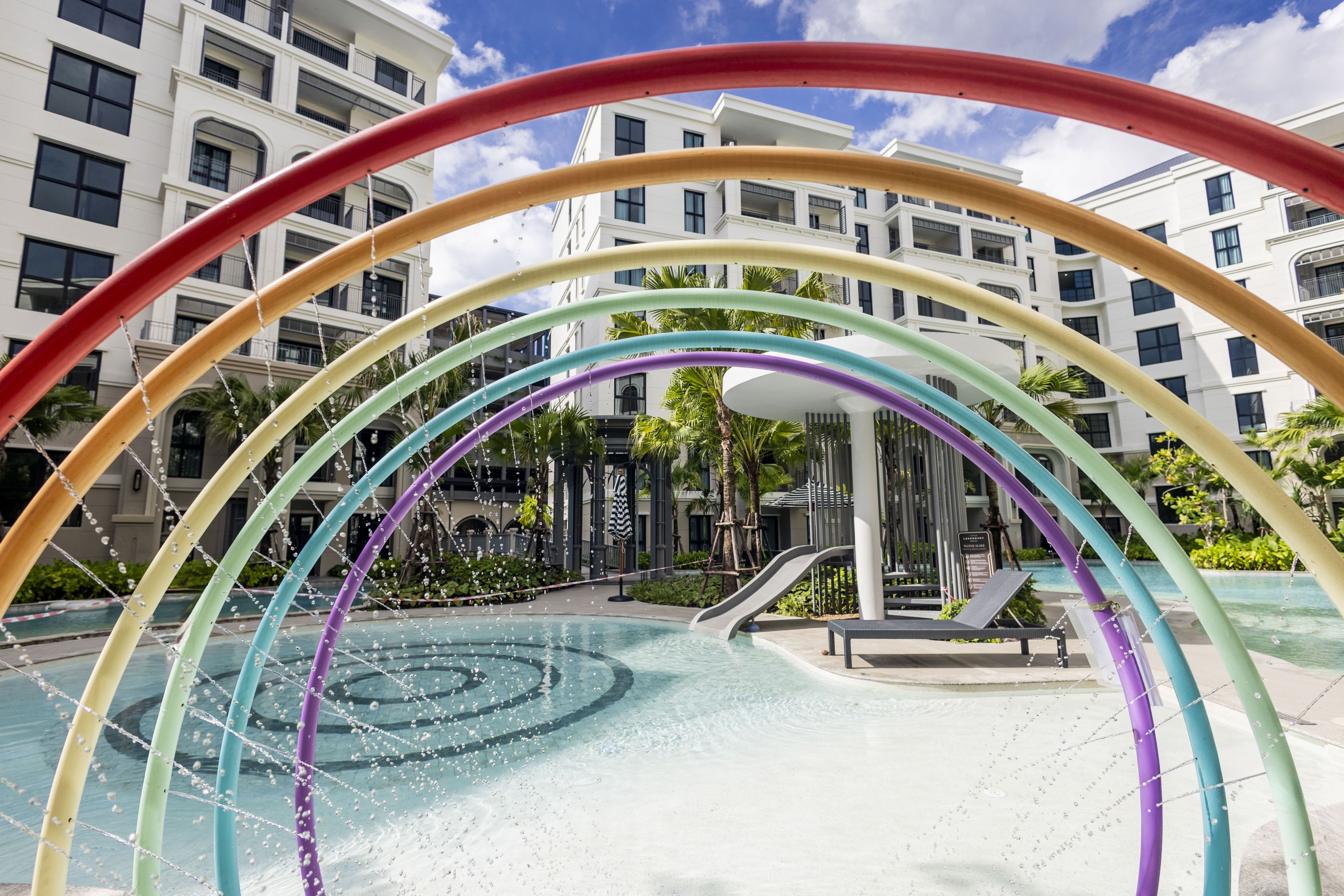 A swimming pool with a rainbow-colored arch structure.