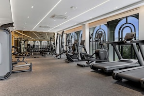 Ein Fitnessstudio mit diversen Trainingsgeräten, darunter Laufbänder und Kraftmaschinen, sowie großen Fenstern mit Blick.