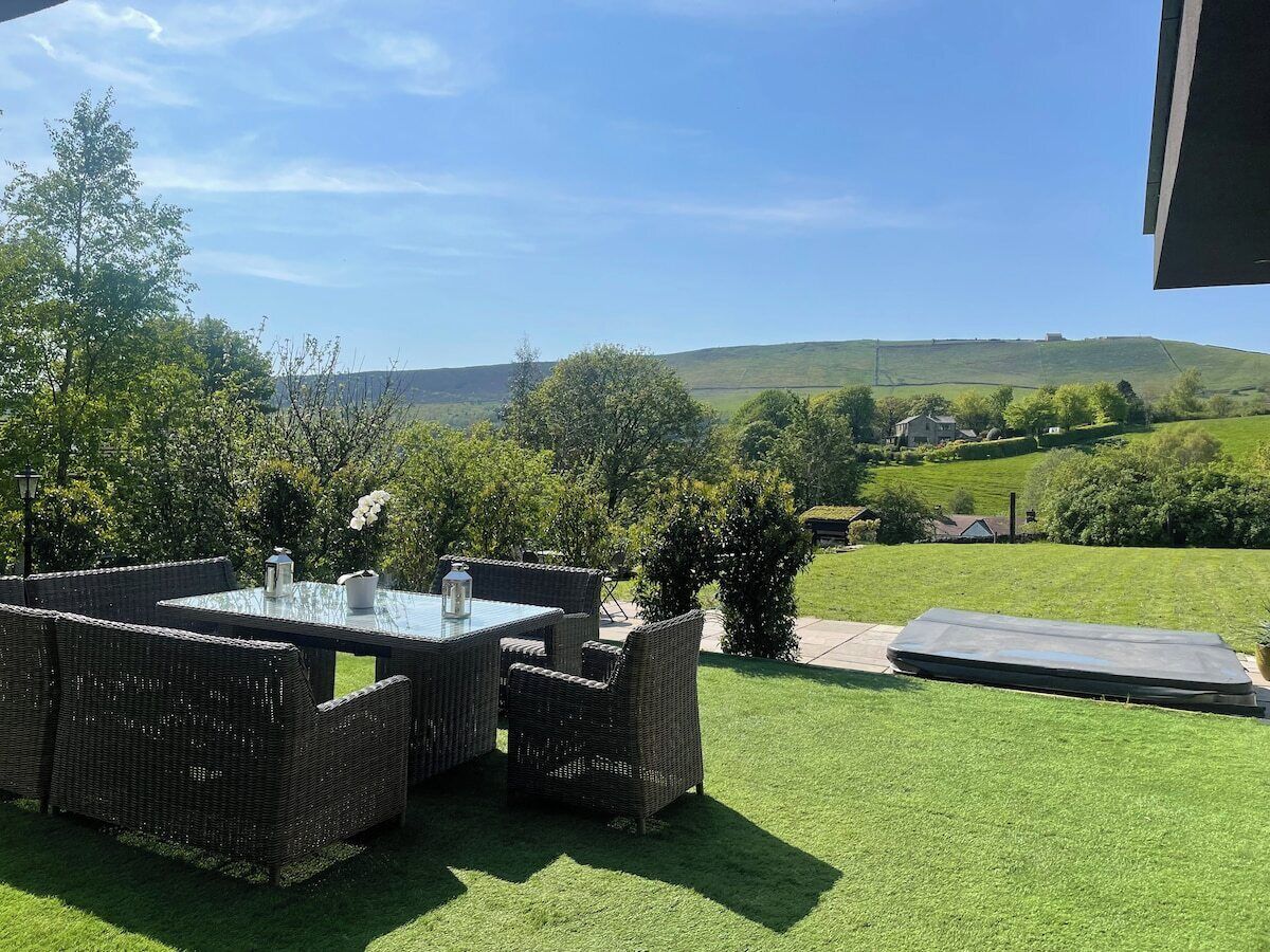 Une terrasse extérieure avec une table et des chaises, un petit jardin et une vue sur la campagne.