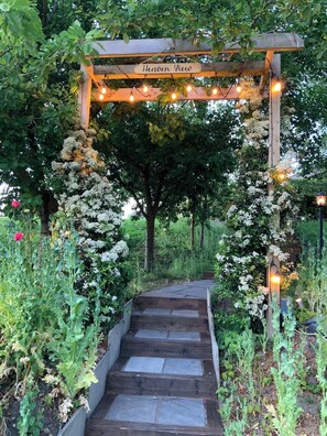 Eine Holz-Pergola mit 'Heaven View' Schild, Steinstufen und Lichterketten.