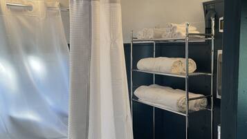A bathroom with a shower curtain, a sink, and a towel rack with neatly folded towels.