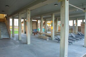 A spacious indoor area with concrete flooring, wooden beams, and a staircase leading to an upper level.