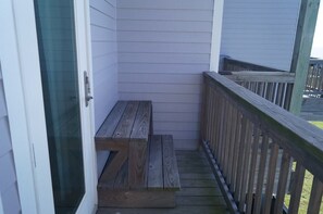 A wooden bench on a porch with a wooden railing. - Casa Dora Beach View Wave (Bolivar Peninsula)