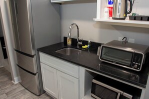 A kitchen with a stainless steel refrigerator, a microwave, and a sink with a faucet.