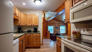A kitchen with wooden cabinets, a refrigerator, a microwave, and a stove.