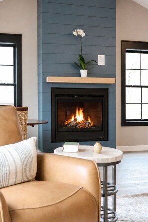 A living room with a fireplace, a leather sofa, a small round table, and a potted plant. - Stay relax recharge, indulge in the perfect escape (Saugerties)