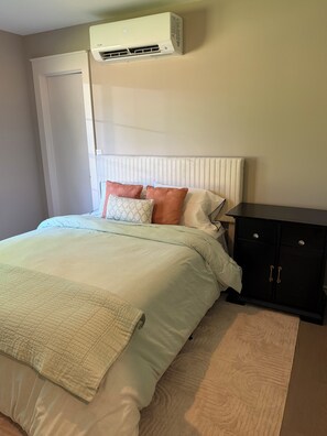 A bedroom with a bed, a bedside table, a wardrobe, and an air conditioning unit mounted on the wall. - Stay relax recharge, indulge in the perfect escape (Saugerties)