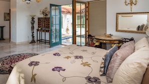 A bedroom with a bed, a round table, a mirror, and a view of the outside. - Buena Vista Farm by Avantstay Spanish Villa + Pool 340-acre Estate (Paso Robles)
