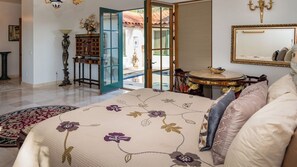 Ein Schlafzimmer mit einem Bett, einem runden Tisch, einem Spiegel und Blick ins Freie.