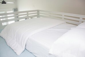 Ein weißes Bett mit schlichtem Kopfteil und einer hellblauen Matratze.