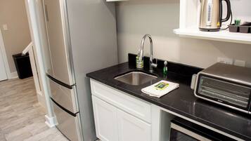 A modern kitchen with a stainless steel refrigerator, a built-in oven, a coffee maker, and a kettle on the countertop.
