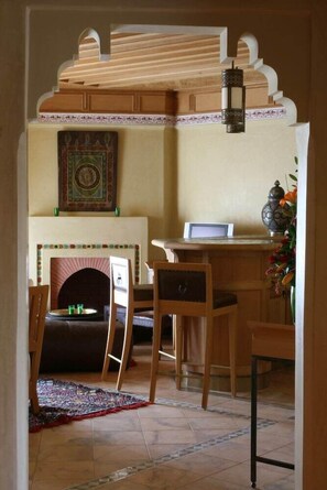 A room with a fireplace, a desk with a laptop, and a chair. - Le Pavillon Du Golf (Marrakech)