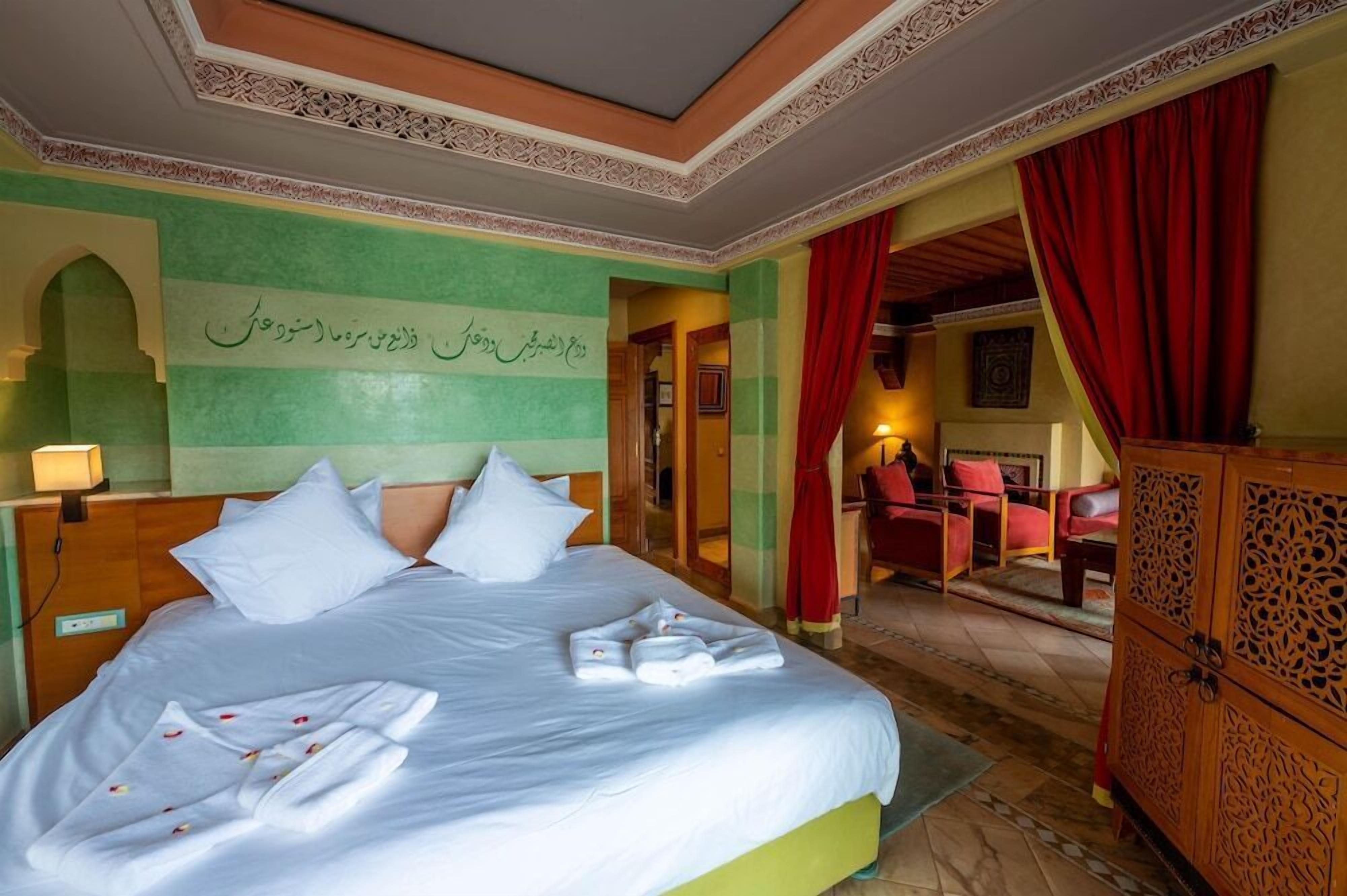 Ein Hotelzimmer mit einem großen Bett, einem Holzschrank und Blick auf einen Essbereich.