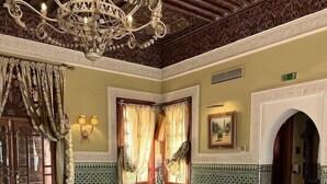 A Moroccan-style room with a chandelier, patterned tiles, a sofa, and a coffee table. - Le Pavillon Du Golf (Marrakech)