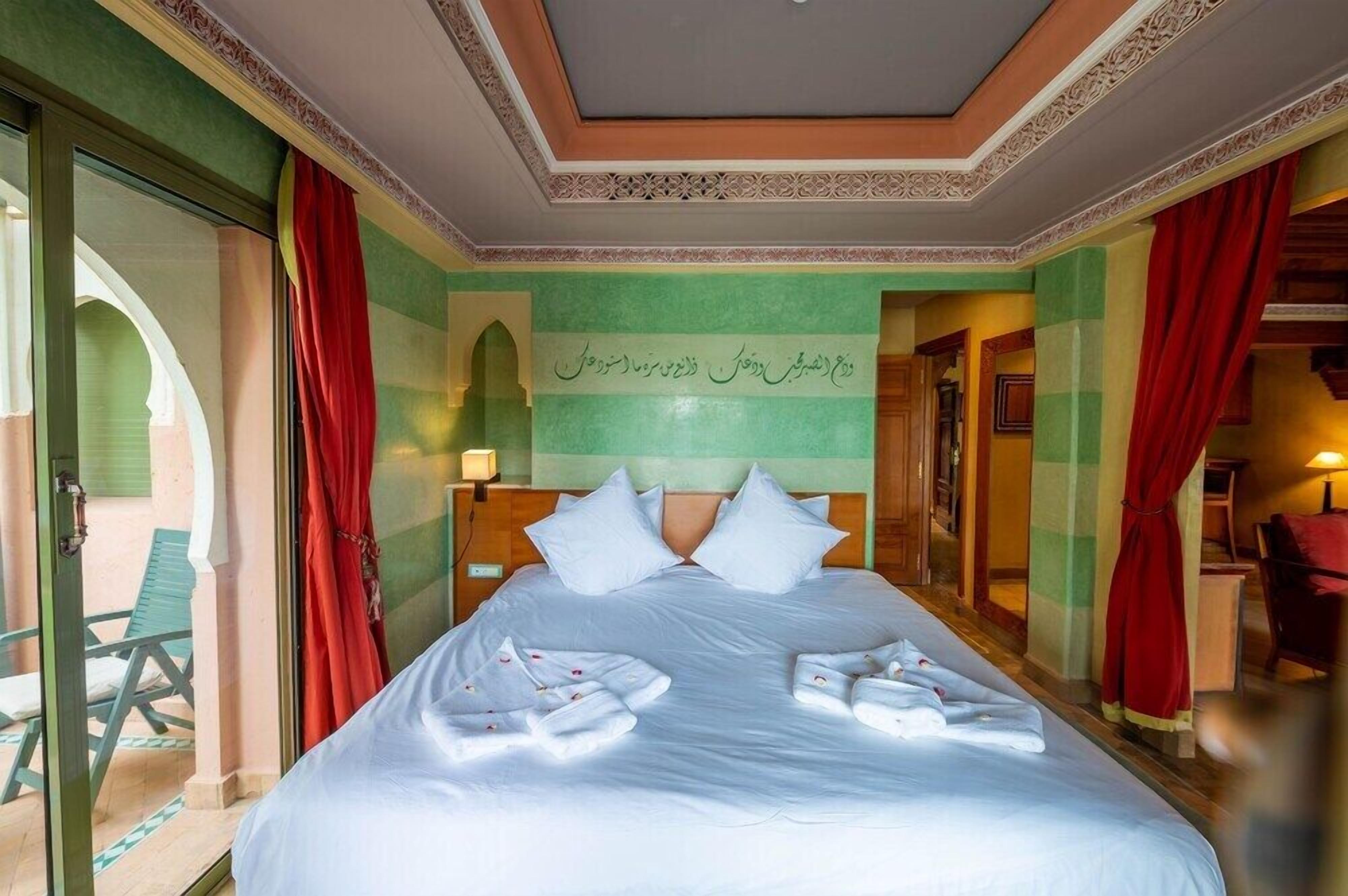 Habitación de hotel con una cama grande, un balcón y vistas a un edificio.