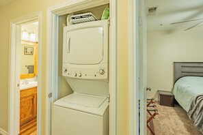Ein kleiner Hauswirtschaftsraum mit Waschmaschine und Trockner, einem Schrank und einem Spiegel.